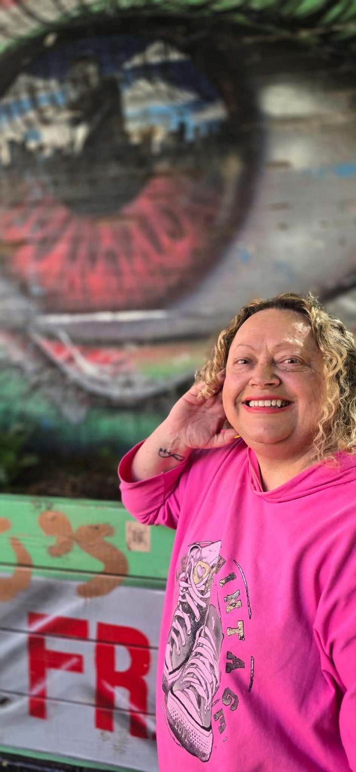 Carol Whiteley smiling in front of a butterfly mural