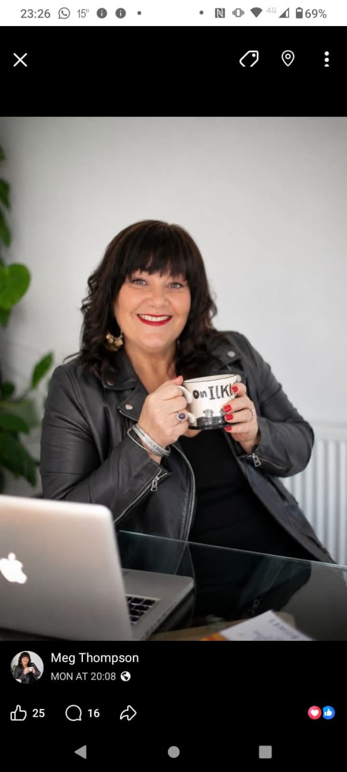 Meg Thompson smiling with a mug beside her laptop